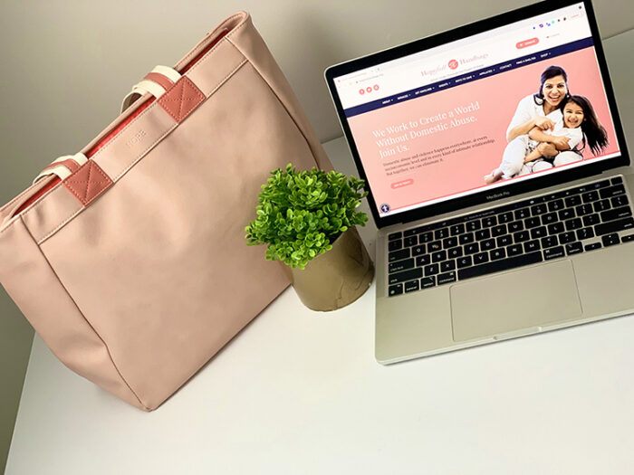 Coral handbag on white desk with small pant and laptop showing Hopefull Handbags webpage