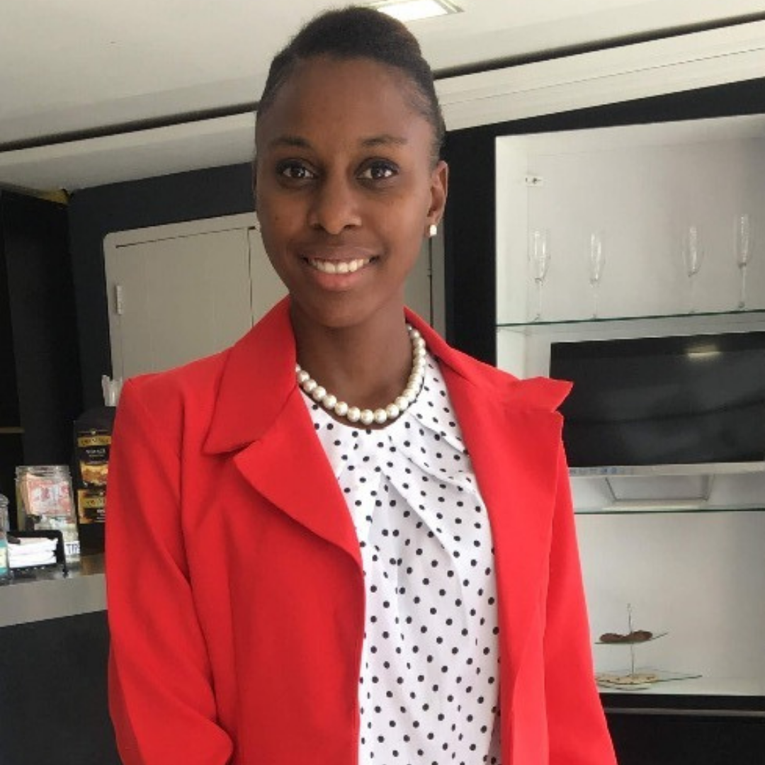Smiling black woman in white blouse with black polka dots and red blazer
